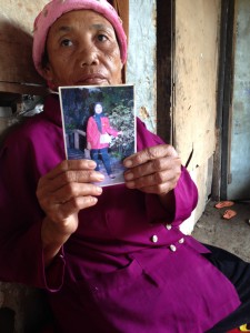 Darasih holds up a photo of her daughter Kartini who works in Saudi Arabia. She has neither heard nor received money from her in the last couple of years., whom she has lost touch with